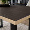 Eine dunkle Tischplatte in Holzoptik mit beigefarbener Kante und schwarzen Beinen ist aus der Nähe zu sehen.
