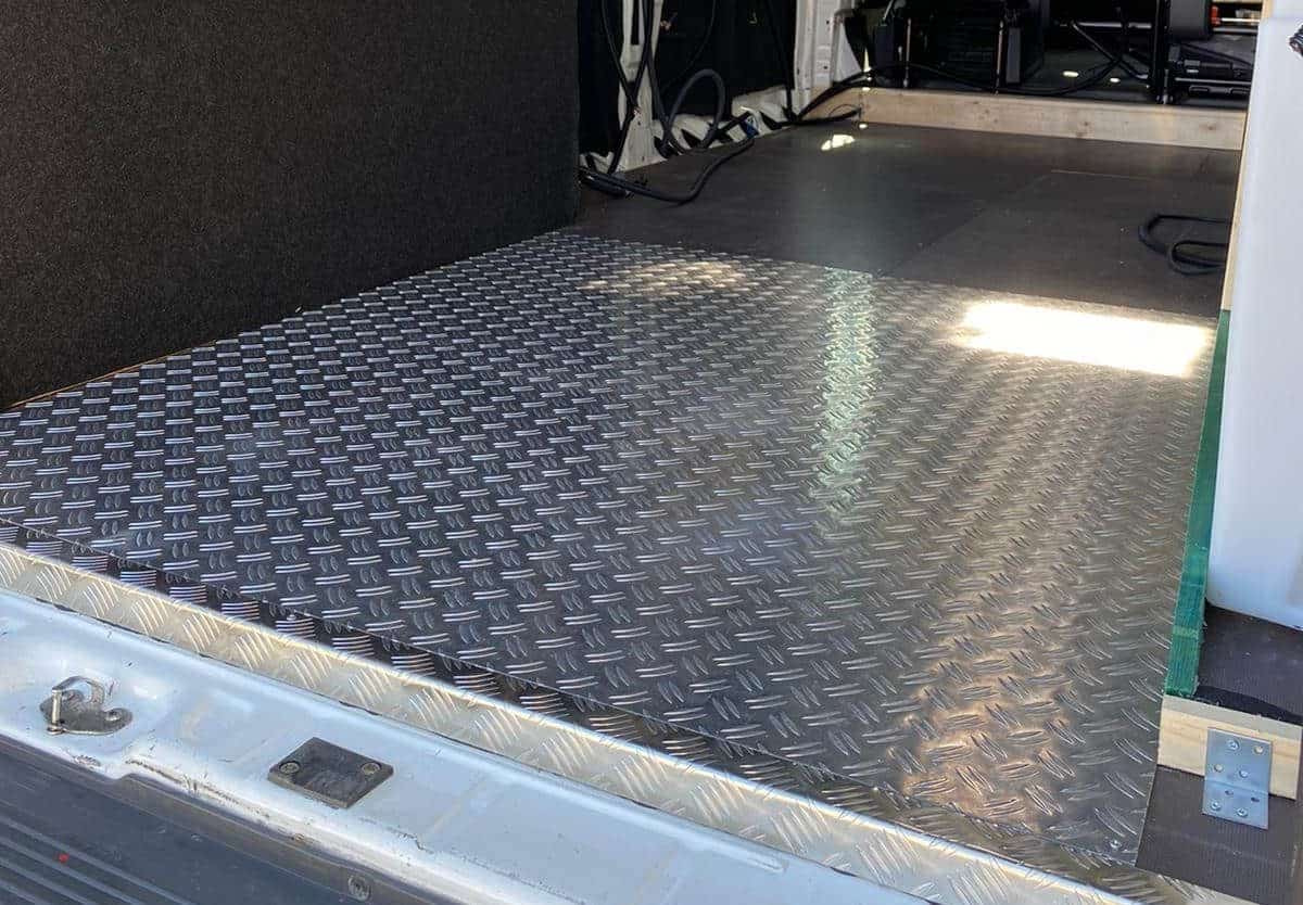 Ein Aluminium-Riffelblechboden legt die stabile Basis des Camper-Ausbaus, während die Wandkonstruktion bereits vorbereitet ist.