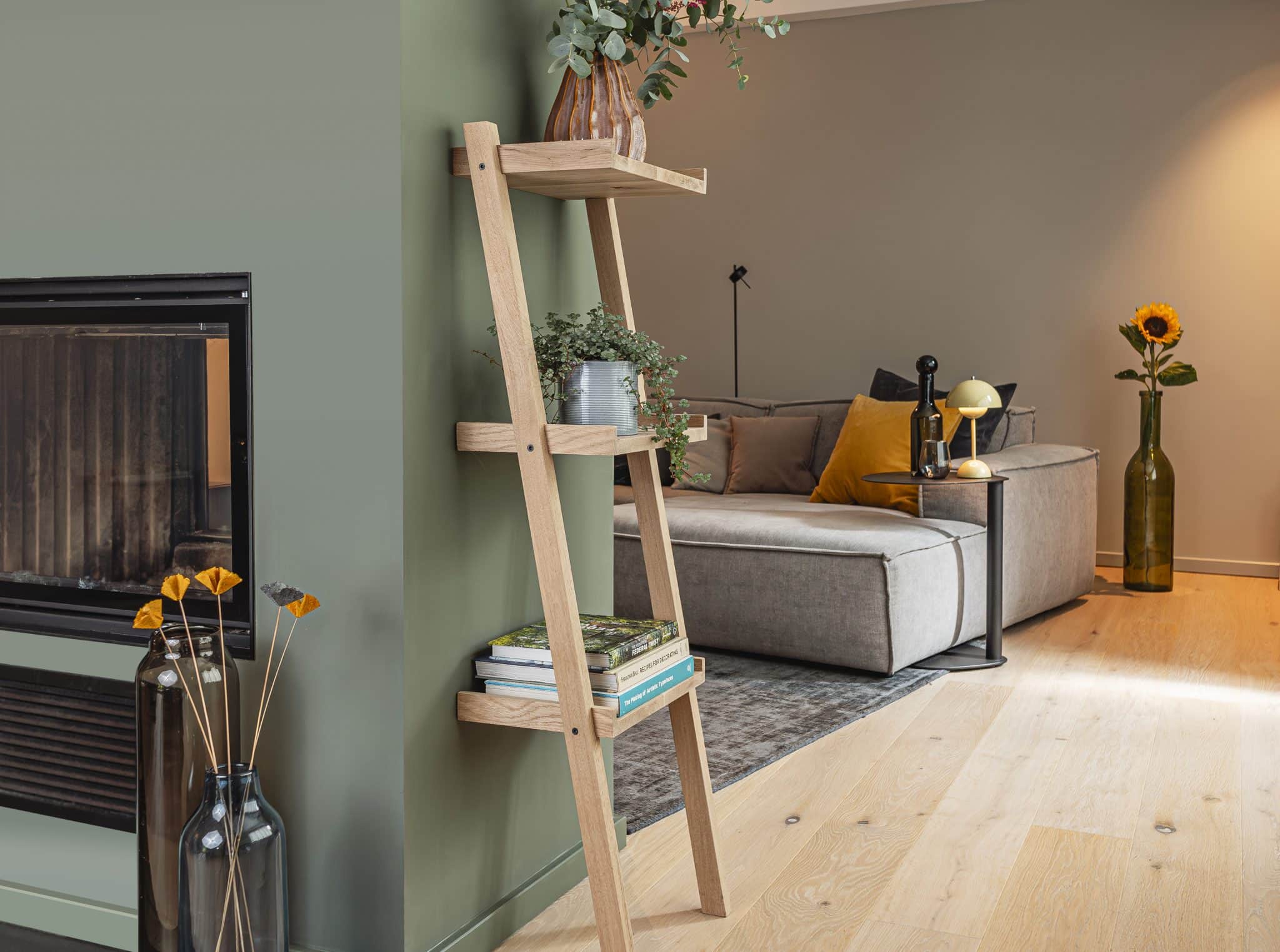 Ein hohes Holzregal mit Pflanzen steht ist in einem modernem Wohnzimmer platziert.