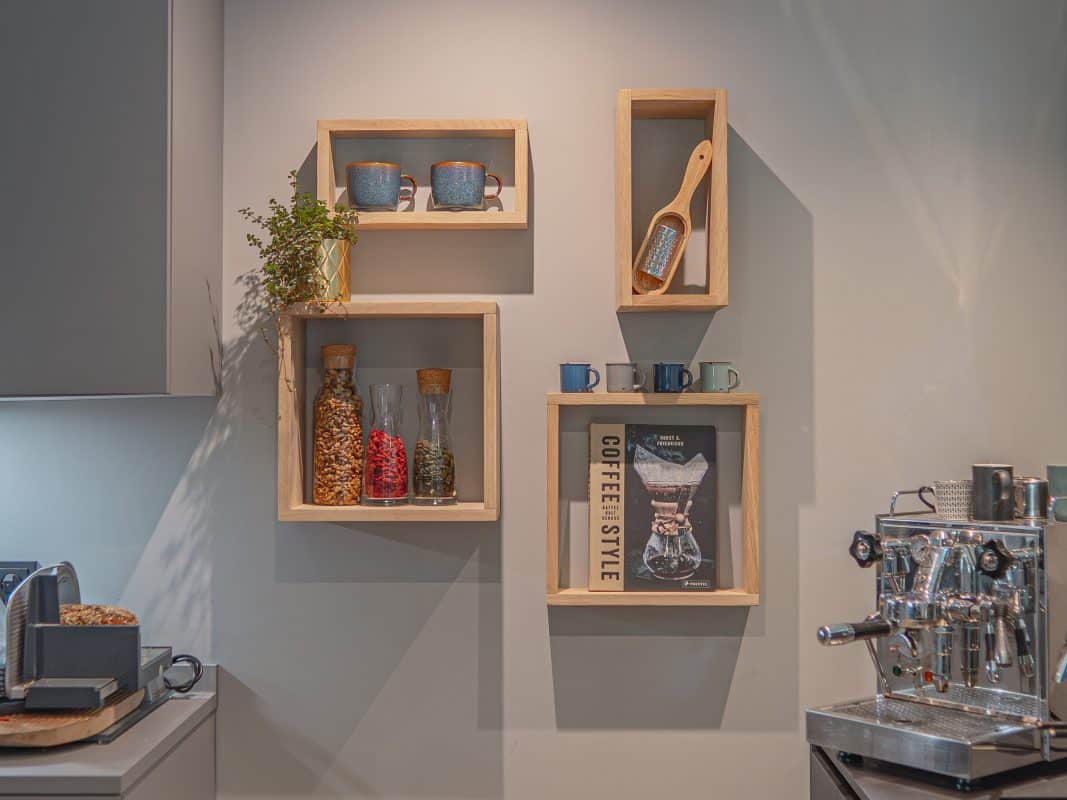 Offene Holzregale mit Tassen, Gewürzen und Kaffeemaschine in moderner Küche.