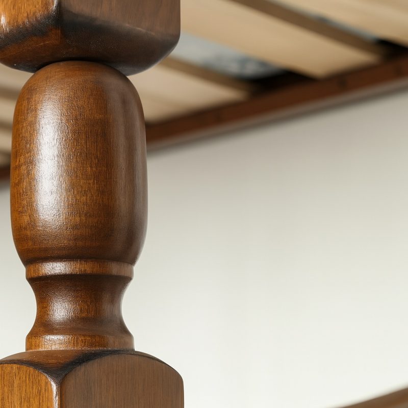 Detailaufnahme eines gedrechselten Holzpfostens mit glatter Oberfläche und natürlicher Maserung vor hellem Hintergrund.