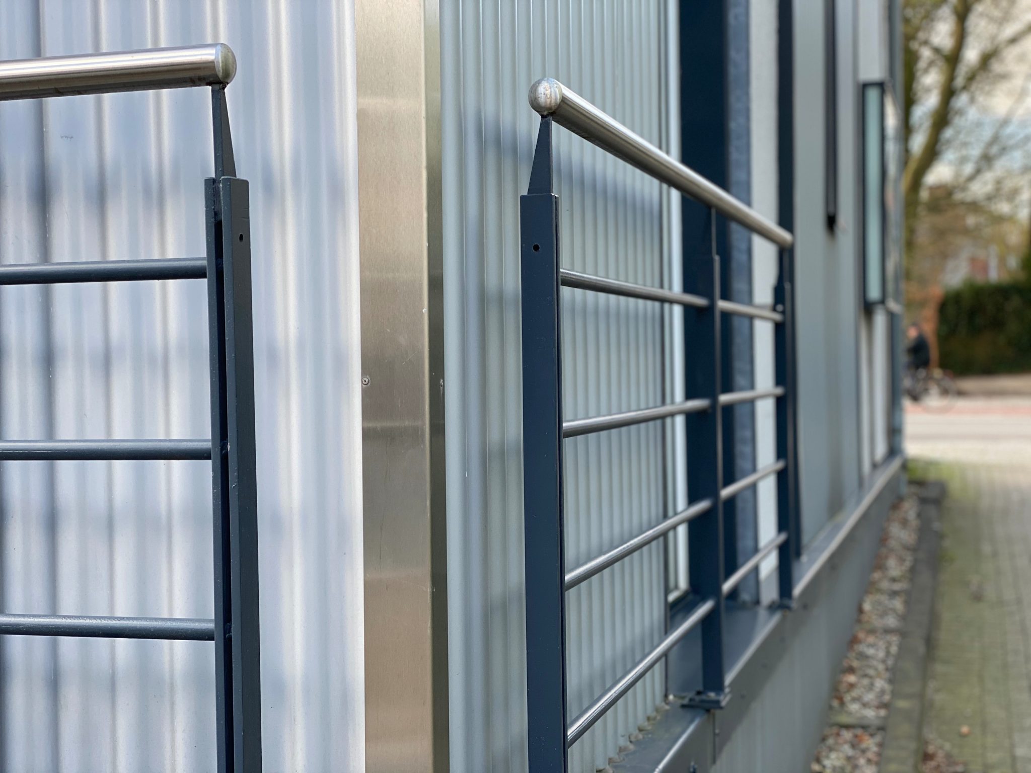 Edelstahl-Kantenschutz an Hausecke mit Metallgeländer.