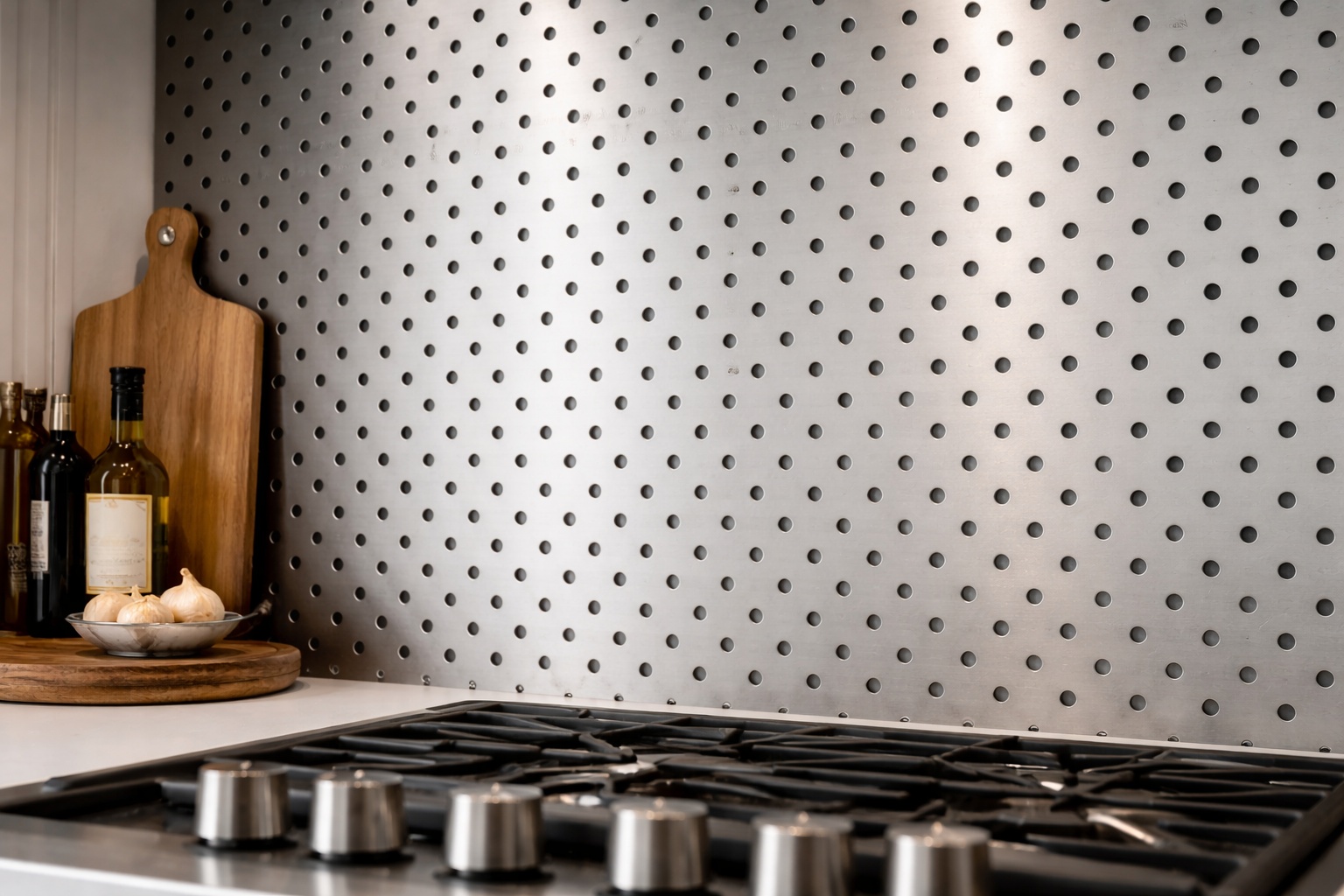 Rund gelochtes Edelstahl-Lochblech bildet eine durchgängige, pflegeleichte Küchenrückwand mit industrieller Wirkung.