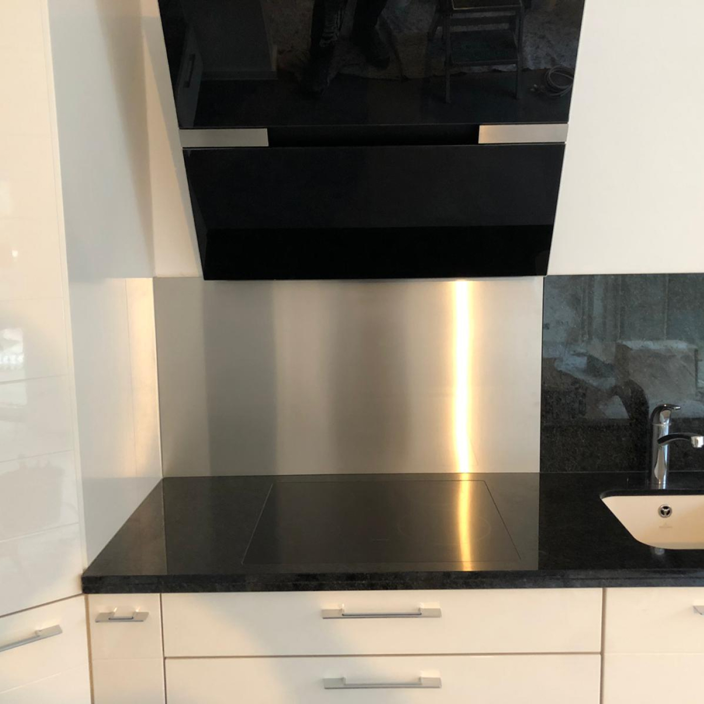 Edelstahl Küchenrückwand hinter Kochfeld und Spüle.