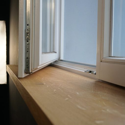 Fensterbank aus massiver Eiche unter geöffnetem Fenster, glatt geschliffen, natürliche Maserung sichtbar.