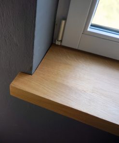 Fensterbank aus massiver Eiche, glatt geschliffen, mit natürlicher Maserung, montiert unter einem Fenster im Innenraum.