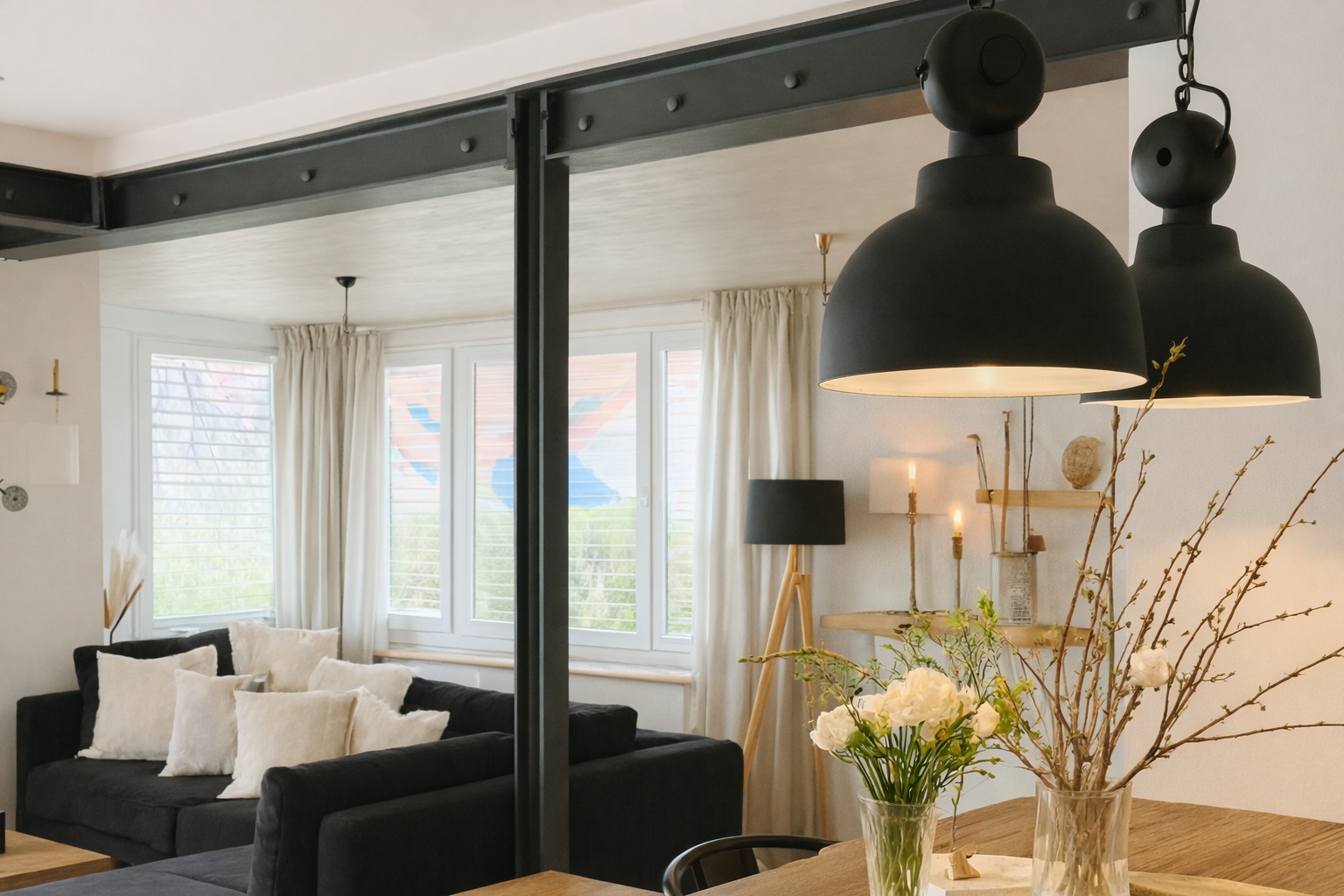 Ein schwarzer HEB-Träger trennt offen den Wohn- und Essbereich eines hellen Wohnraums.