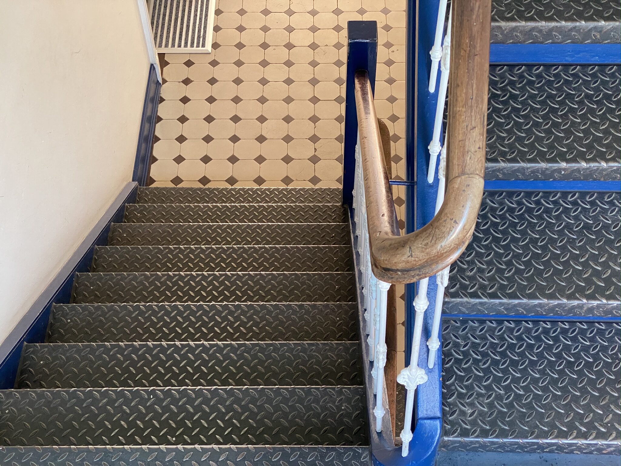 Eine Treppe ist mit Aluminium Riffelblech belegt und besitzt ein Holzhandlaufgeländer.