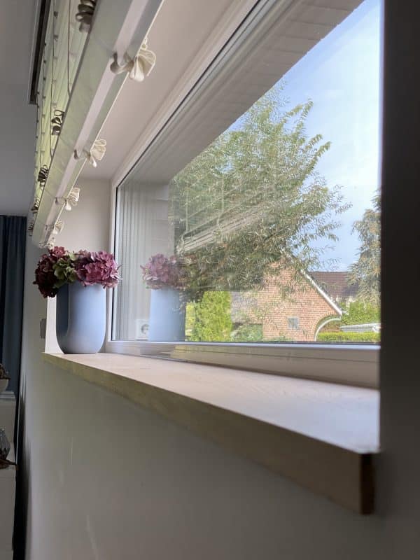 Fensterbank mit einer Vase und Blick ins Grüne.