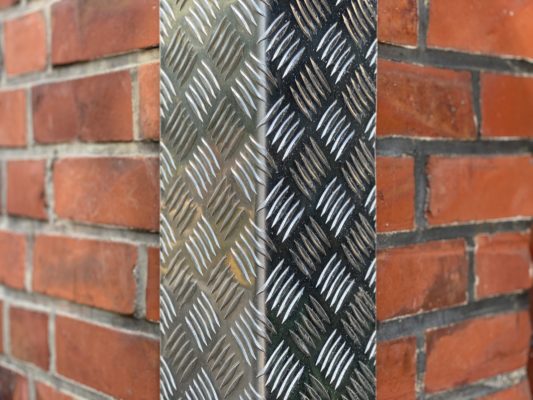 Aluminium-Riffelblech mit markanter Struktur setzt einen robusten Akzent an der Backsteinwand.