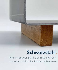 Ein beschichteter Kaminholzständer aus Schwarzstahl steht auf einem Holzsockel.