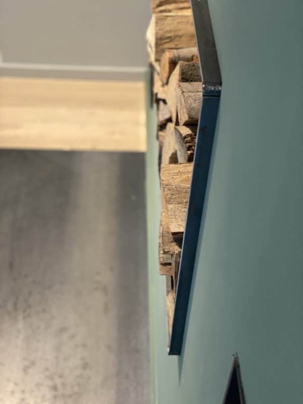 Seitenansicht eines Holzlagers an der Wand mit angrenzender Funkenschutzplatte.