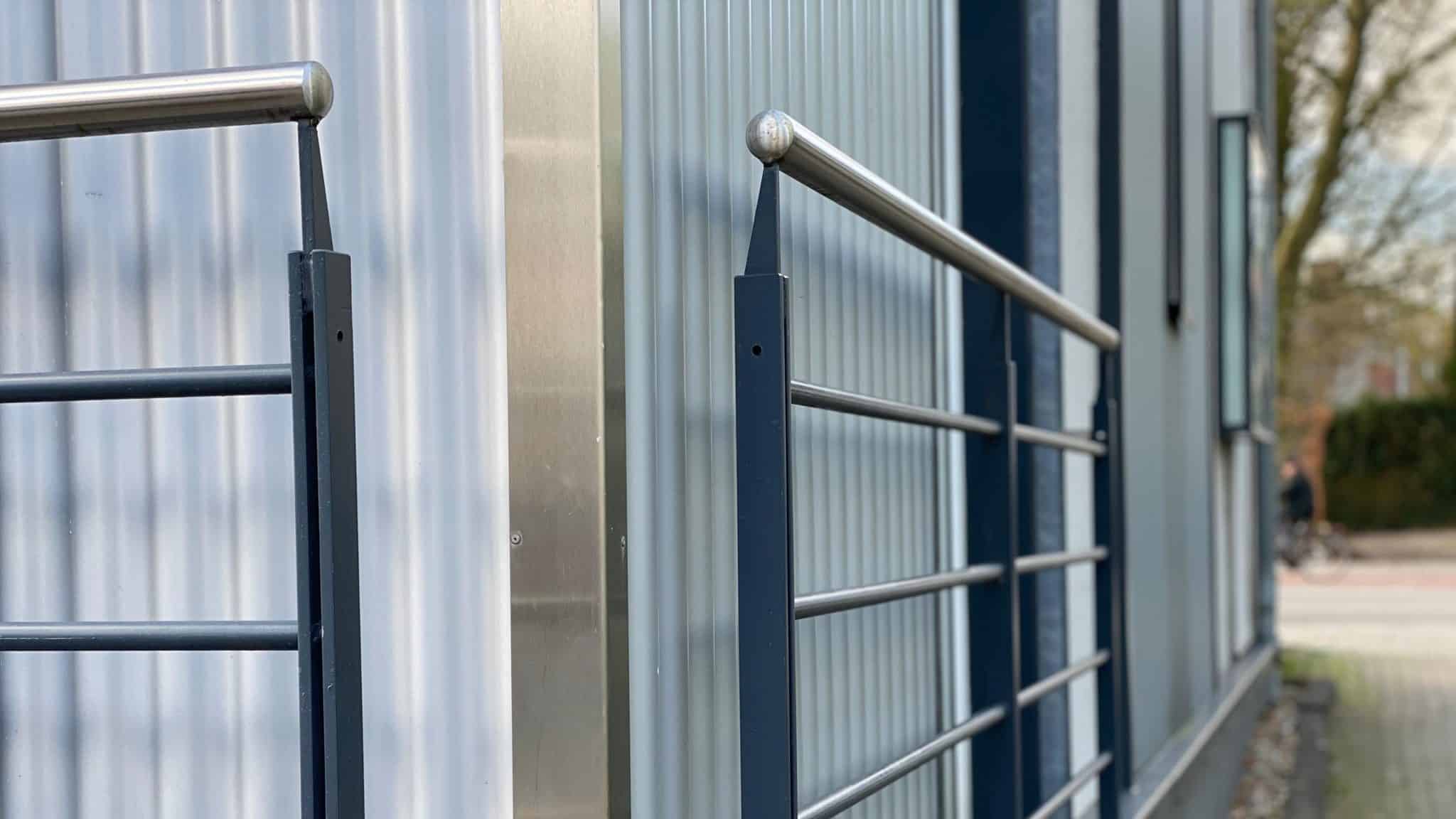 Ein schlichtes Edelstahlgeländer mit runden Stäben verläuft an einer modernen Fassade.