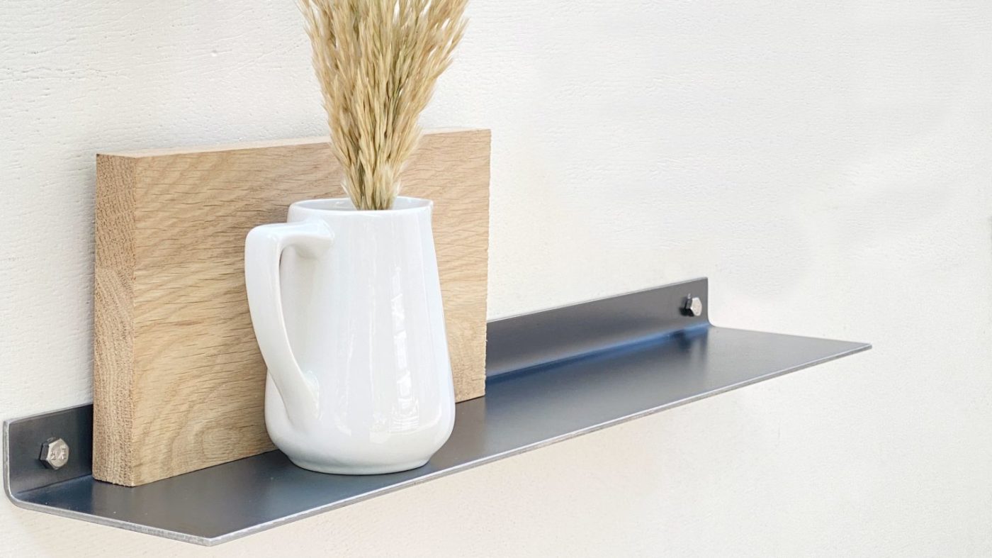 Schwarzes Metallregal mit weißer Vase und Holzdeko.