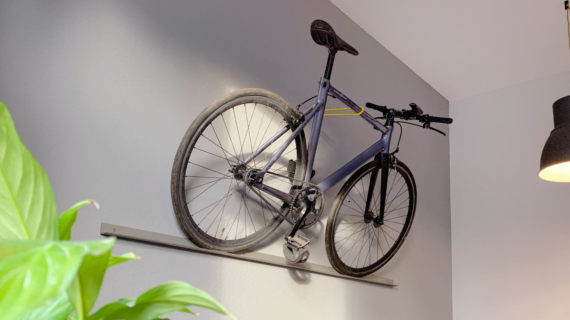 Ein L-Profil aus Stahl wird als minimalistischer Fahrradhalter an der Wand genutzt.