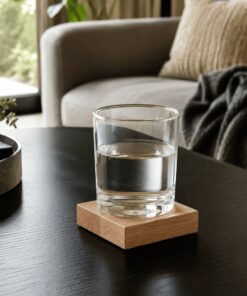 Ein Wasserglas steht auf einem Eichenuntersetzer auf dem Wohnzimmertisch neben dem Sofa.