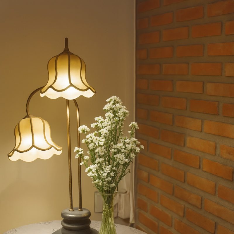 Stehlampe im Retro-Stil neben einer Vase mit weißen Blumen vor Ziegelwand.