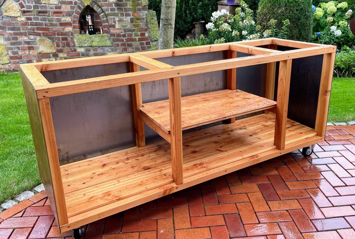 Outdoorküche im Aufbau mit Holzrahmen, Cortenstahlplatten und offenen Ablageflächen
