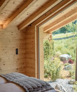 Modernes Tiny House mit großen Fenstern und Blick in den Garten, kompakte Wohnlösung mit naturnahem Wohnerlebnis. Titel: