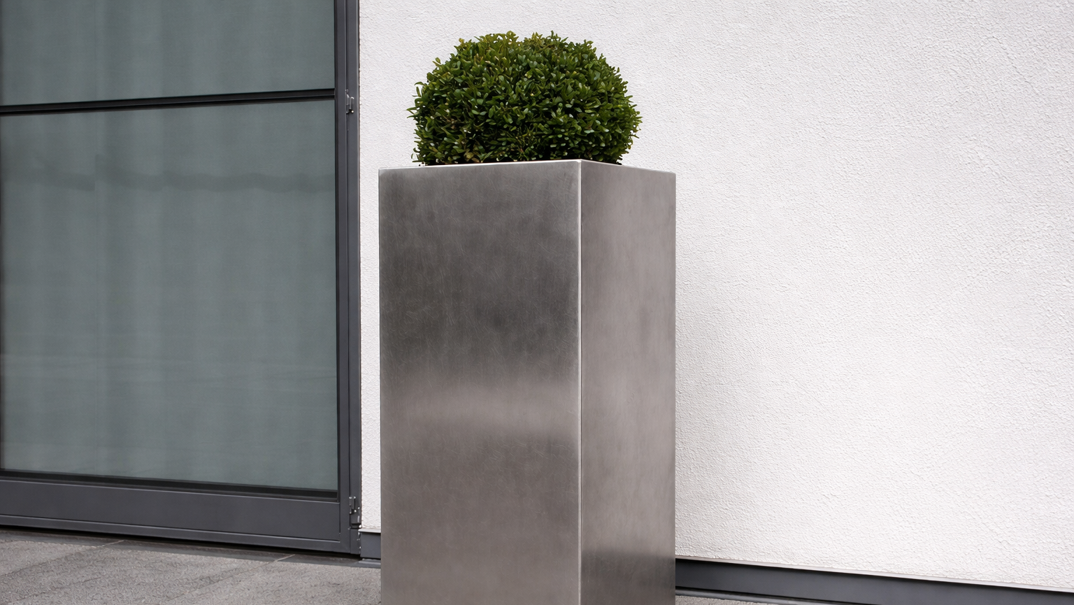 Ein Pflanzkübel aus ungeschliffenem Edelstahl wirkt robust und fügt sich klar in moderne Architektur ein.