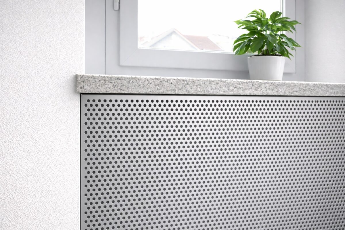 Eine Heizkörperverkleidung aus Lochblech mit runden Lochungen sorgt für gleichmäßige Luftzirkulation.