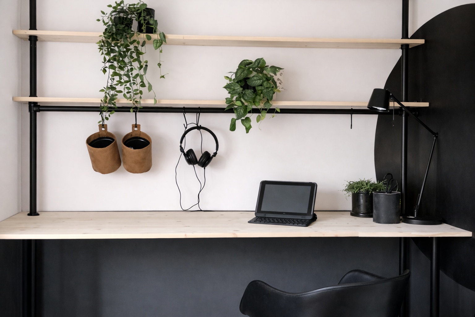 Ein Homeoffice zeigt ein Regal aus Rundrohr Stahl über dem Schreibtisch.