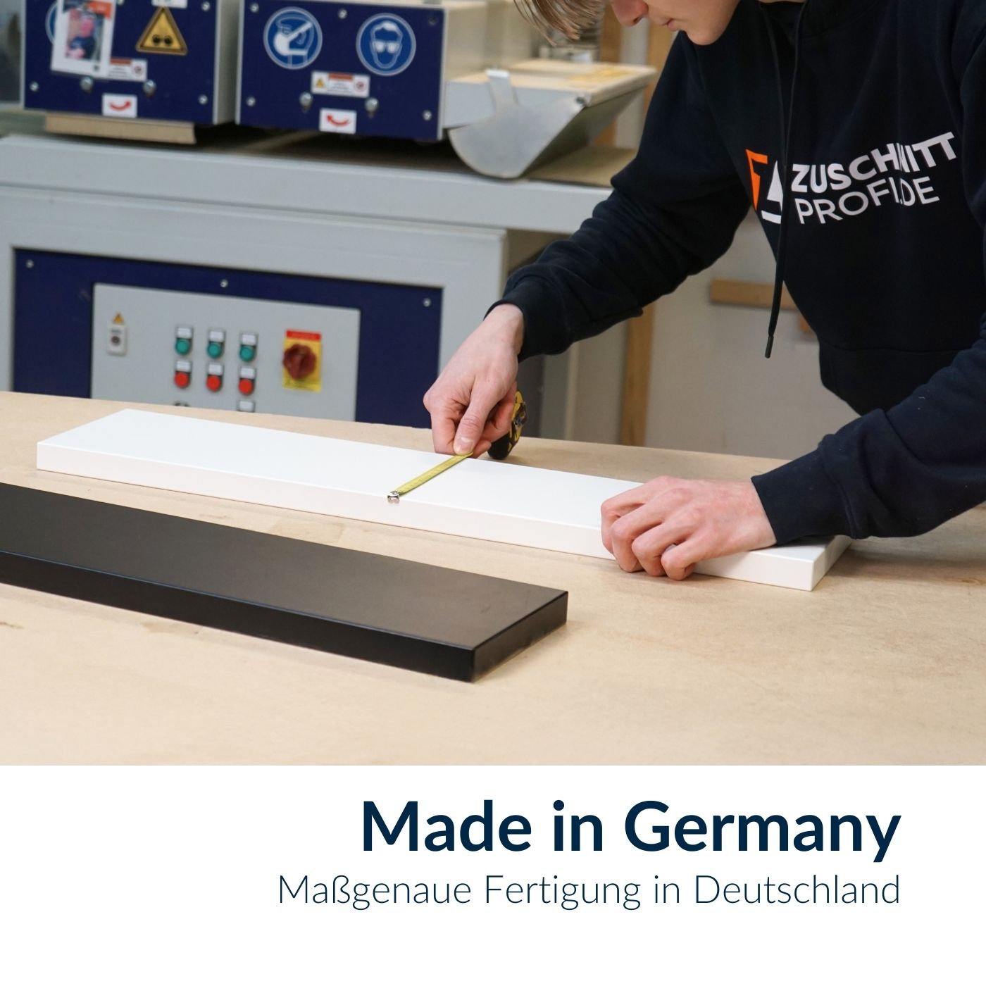 Mitarbeiter misst eine weiße Smart+ Dekorplatte mit einem Maßband in der Werkstatt aus.