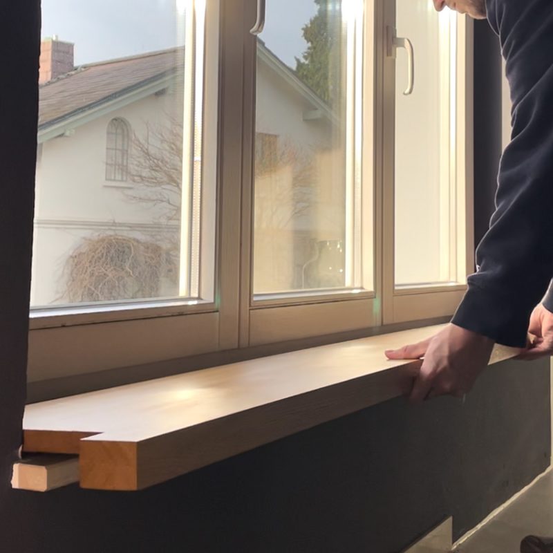 Eingebaute Holzfensterbank aus massiver Eiche in Nahaufnahme, glatt geschliffen und natürlich gemasert.