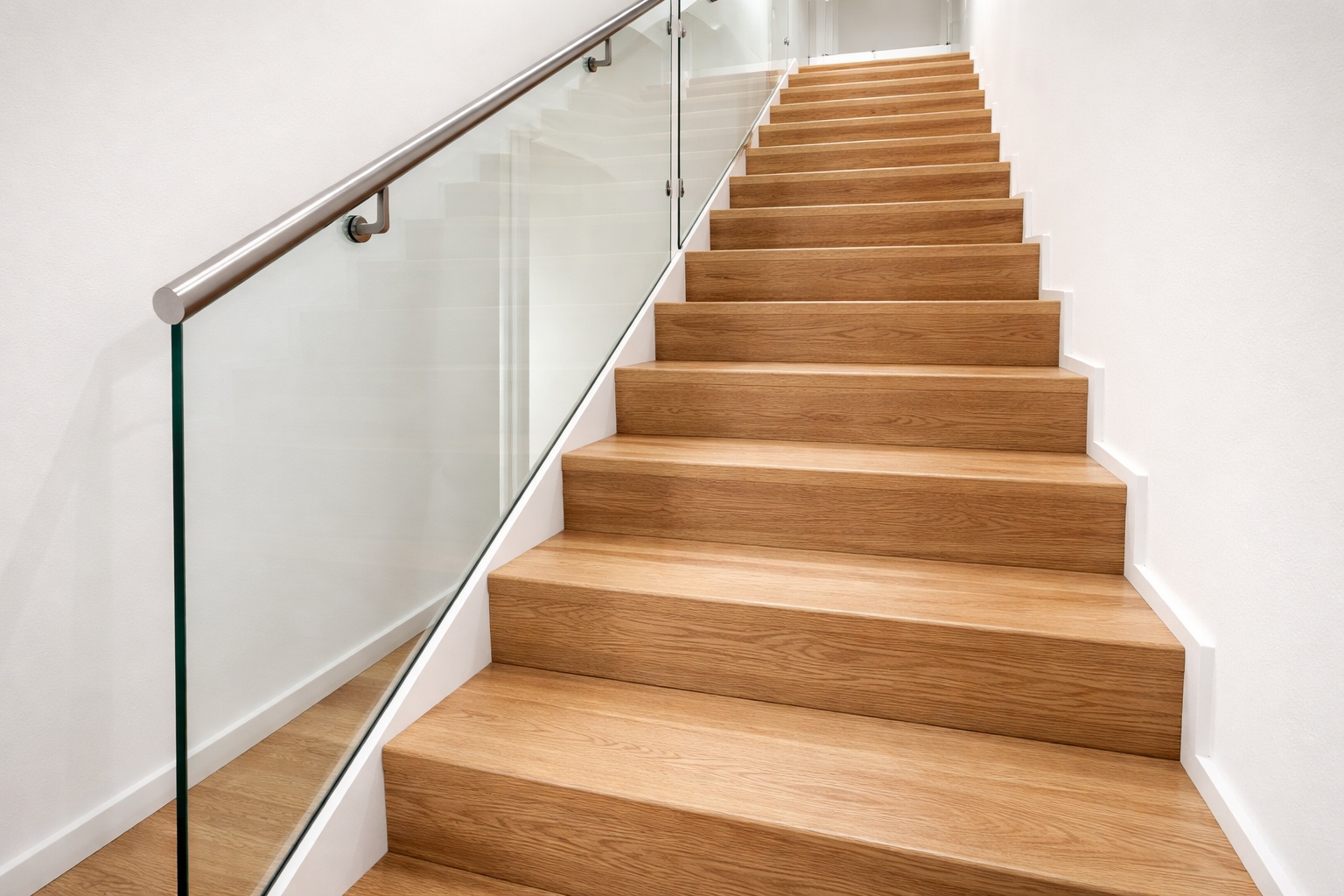Offene Treppe mit massiven Eichenstufen und Glasgeländer in moderner Architektur.