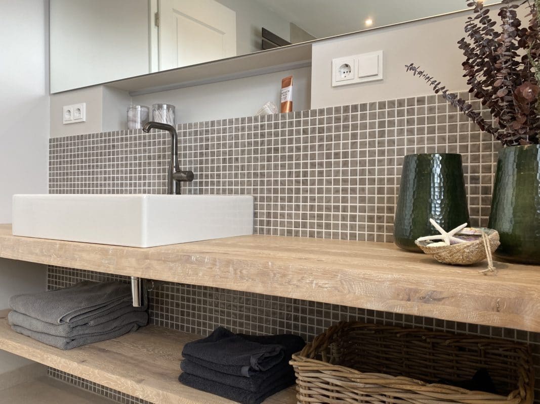 Moderner Holzwaschtisch mit quadratischem Waschbecken und Deko.