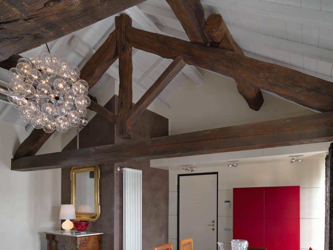 Holzbalken-Decke in modernem Wohnraum mit Designlampe und roten Akzenten.