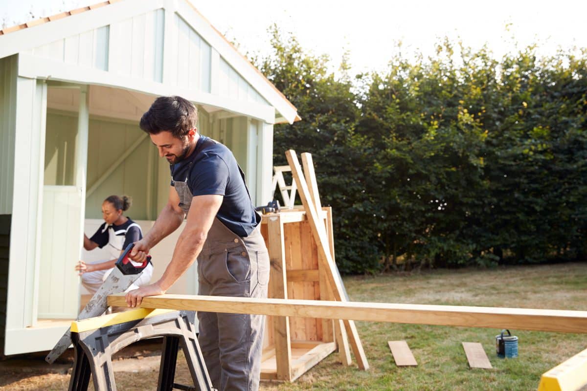 Ein Handwerker sägt an einer Holzlatte.