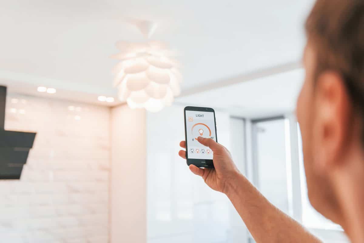Person steuert Wohnzimmerbeleuchtung per Smarthome-App.
