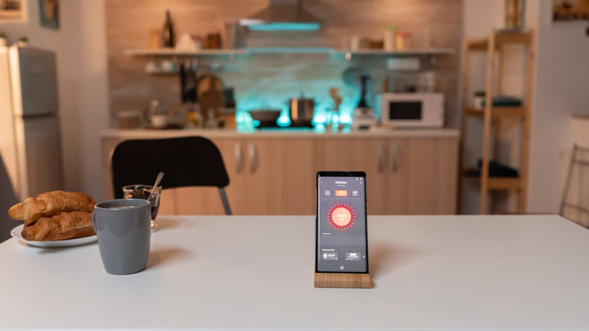 Smartphone steuert Smarthome-Beleuchtung in moderner Küchenumgebung.