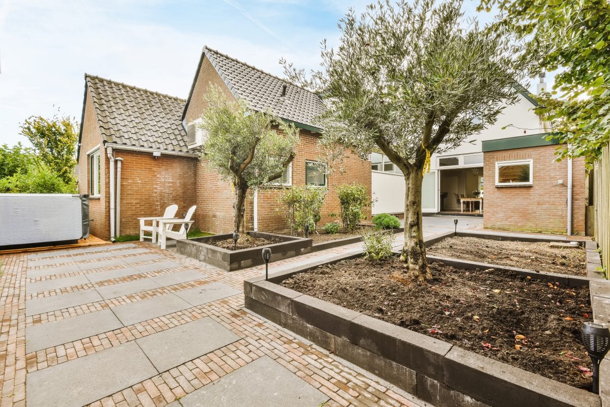 Moderner Hof mit gepflasterten Wegen und Hochbeeten.